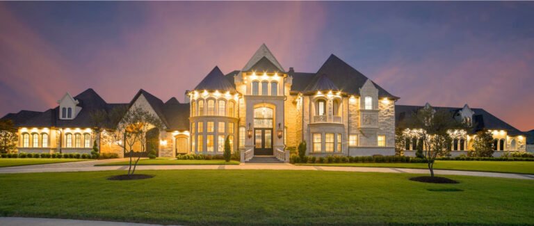 Luxury stone home with manicured lawn at dusk in Dallas-Fort Worth