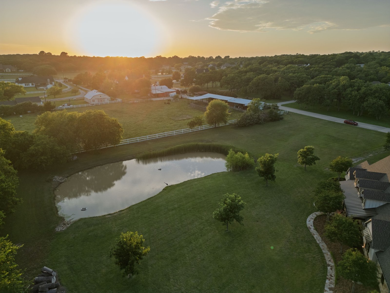 Aerial view at sunset of an acreage property with a pond and pasture in Keller, TX 76262