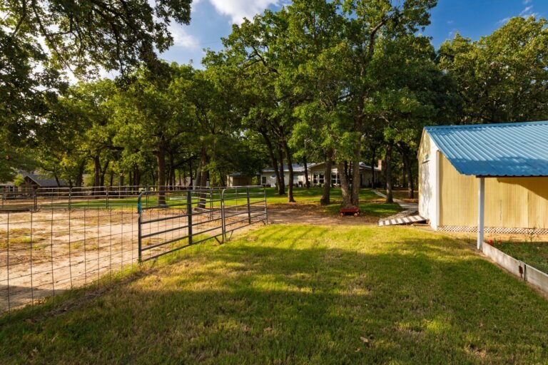 Storage shed beside a fenced pen under mature trees at 1311 Mount Gilead Rd, Keller TX